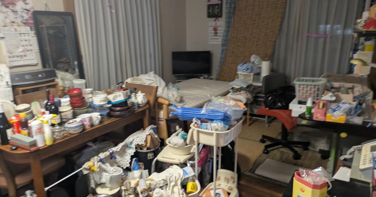 不用品回収前のリビングに家具や衣類、日用品などが大量に置かれている様子