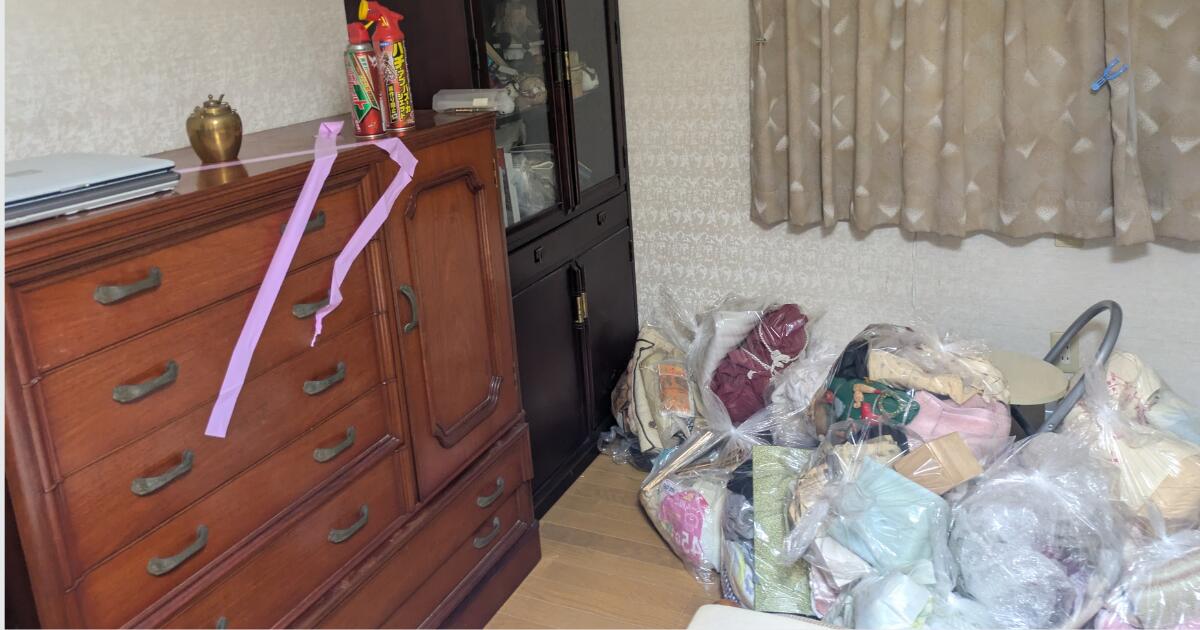 不用品回収前の部屋に大型タンスや飾り棚、袋詰めされた寝具などがある様子